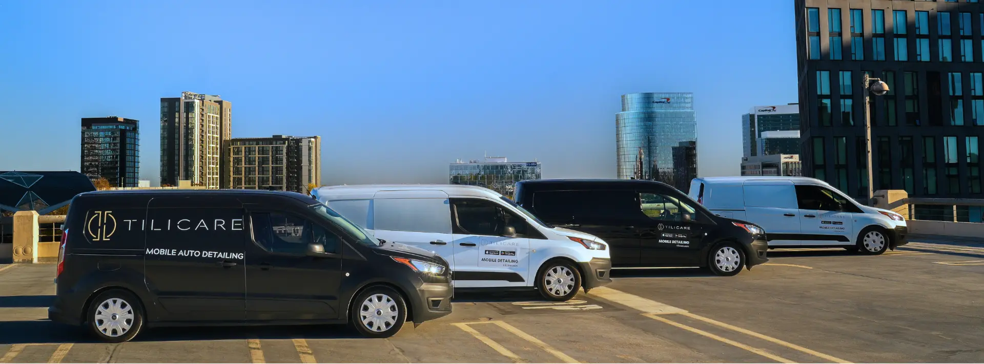 Four Tilicare mobile detailing vans parked in a row on a parking garage rooftop